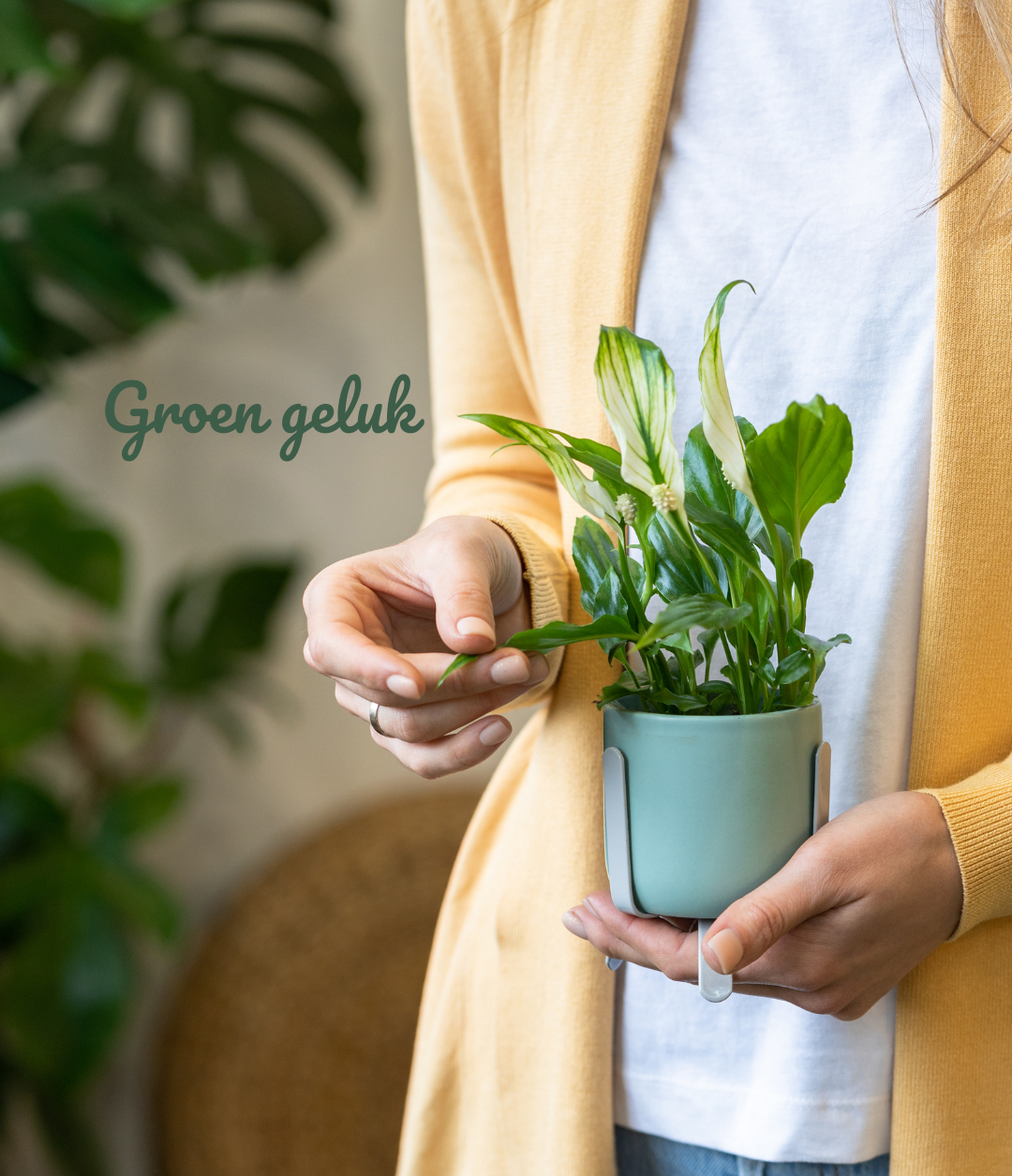 Vrouw in gele cardigan houdt een groene kamerplant vast en raakt het blad aan, met de tekst “Groen geluk” op de achtergrond